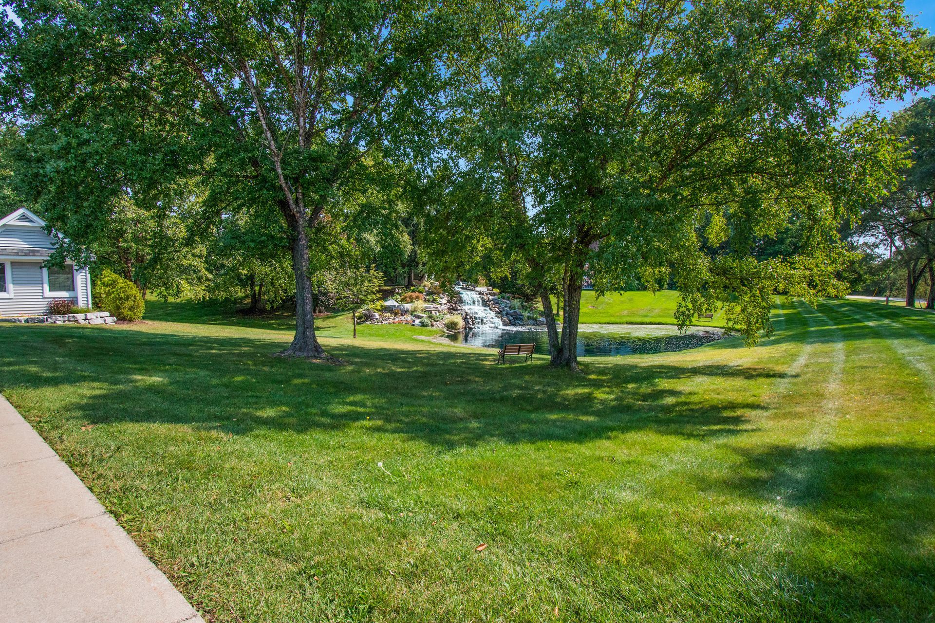 A lush green lawn with trees and a house in the background.