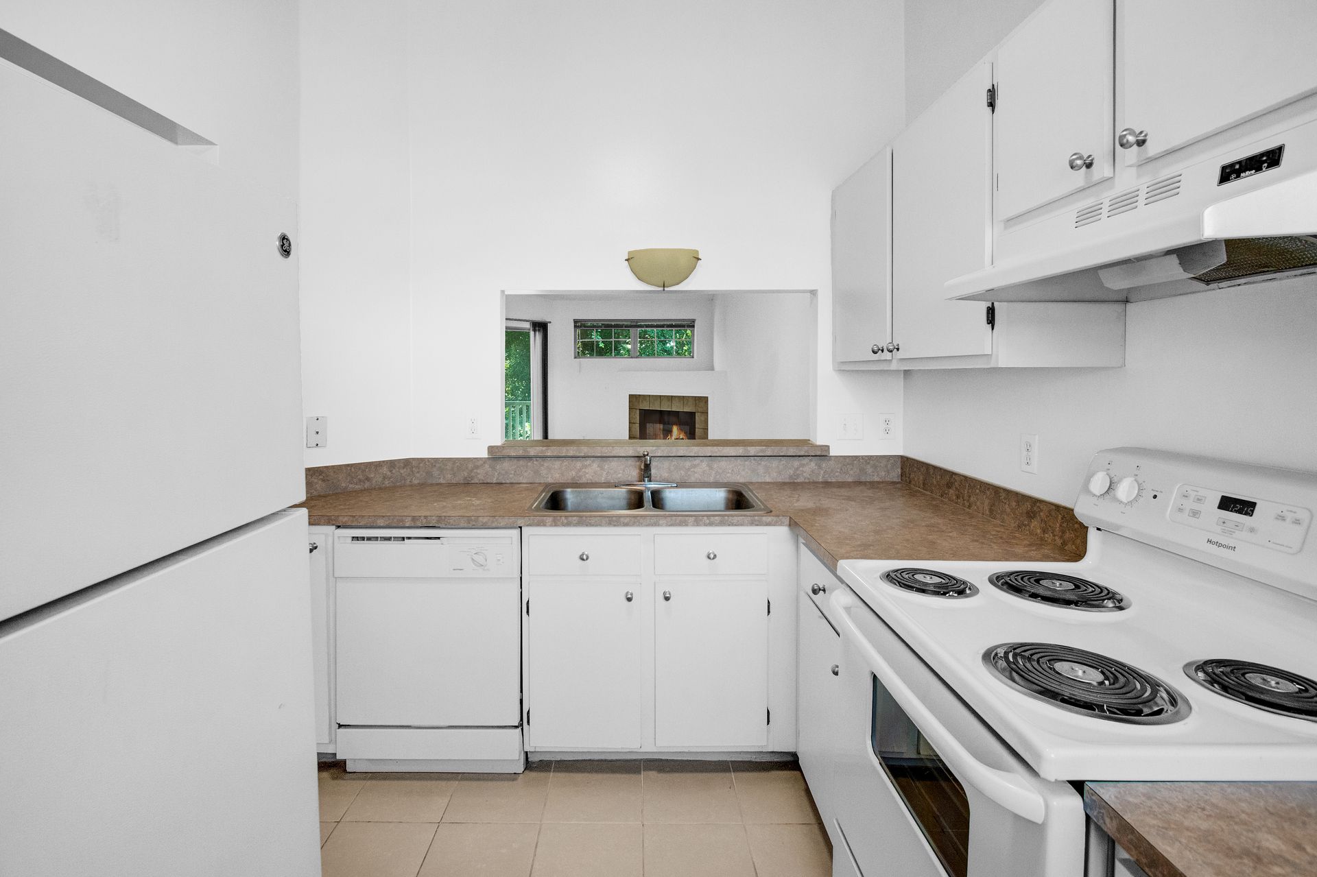 A kitchen with white cabinets , a stove , a refrigerator , and a sink.