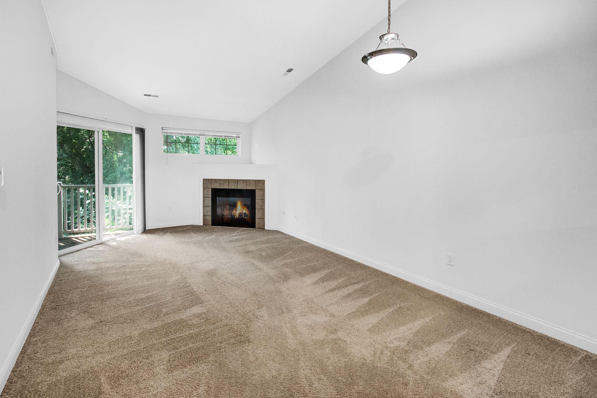 An empty living room with a fireplace and sliding glass doors.