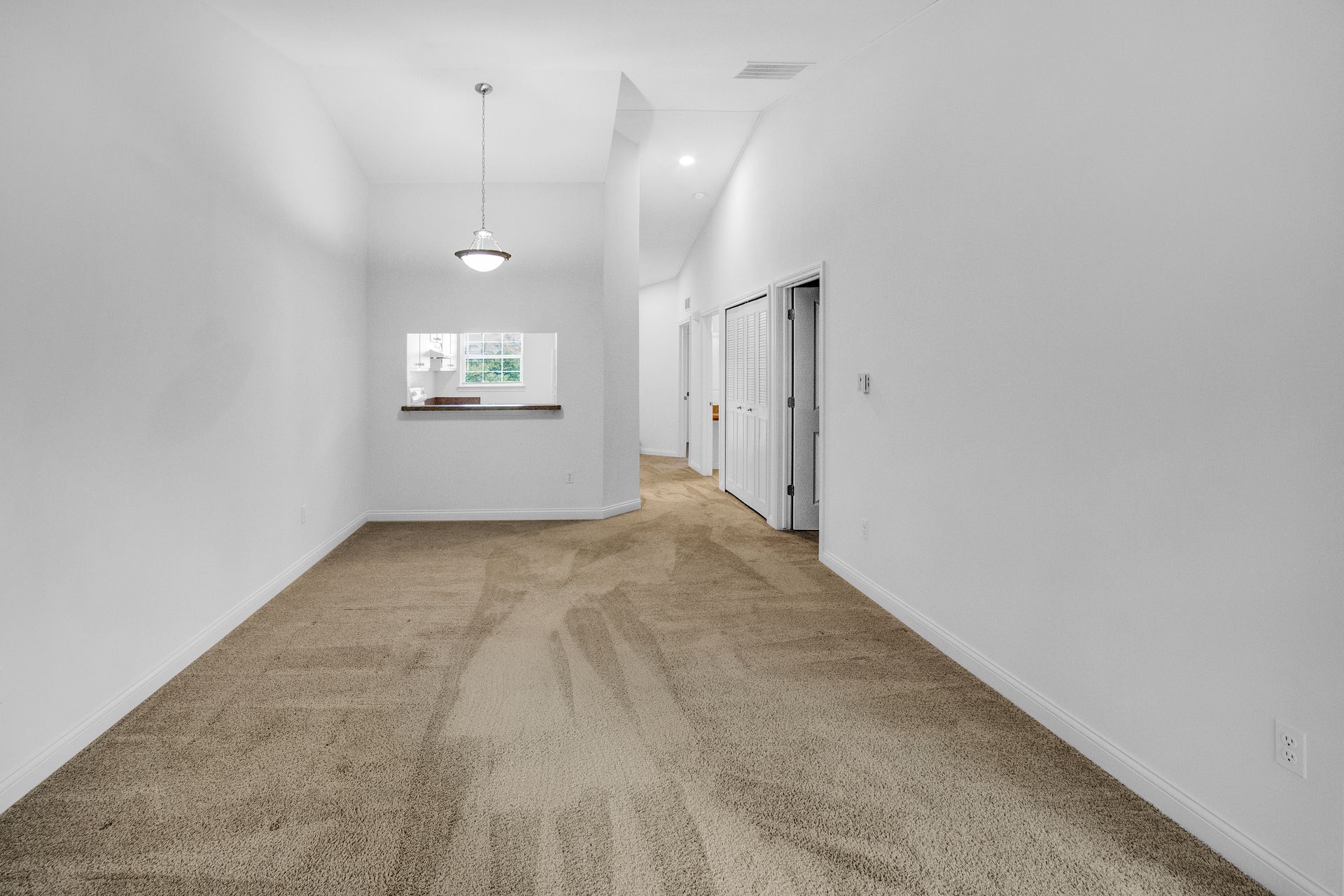 An empty room with a brown carpet and white walls.