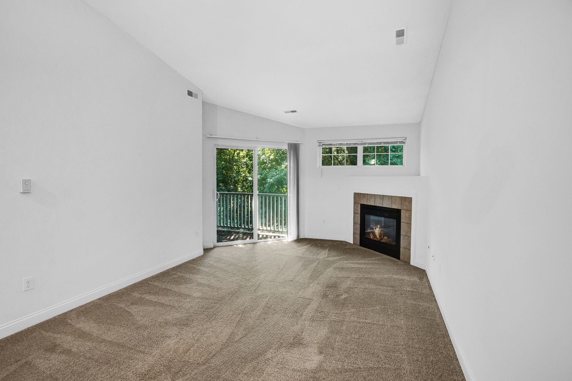 An empty living room with a fireplace and sliding glass doors.