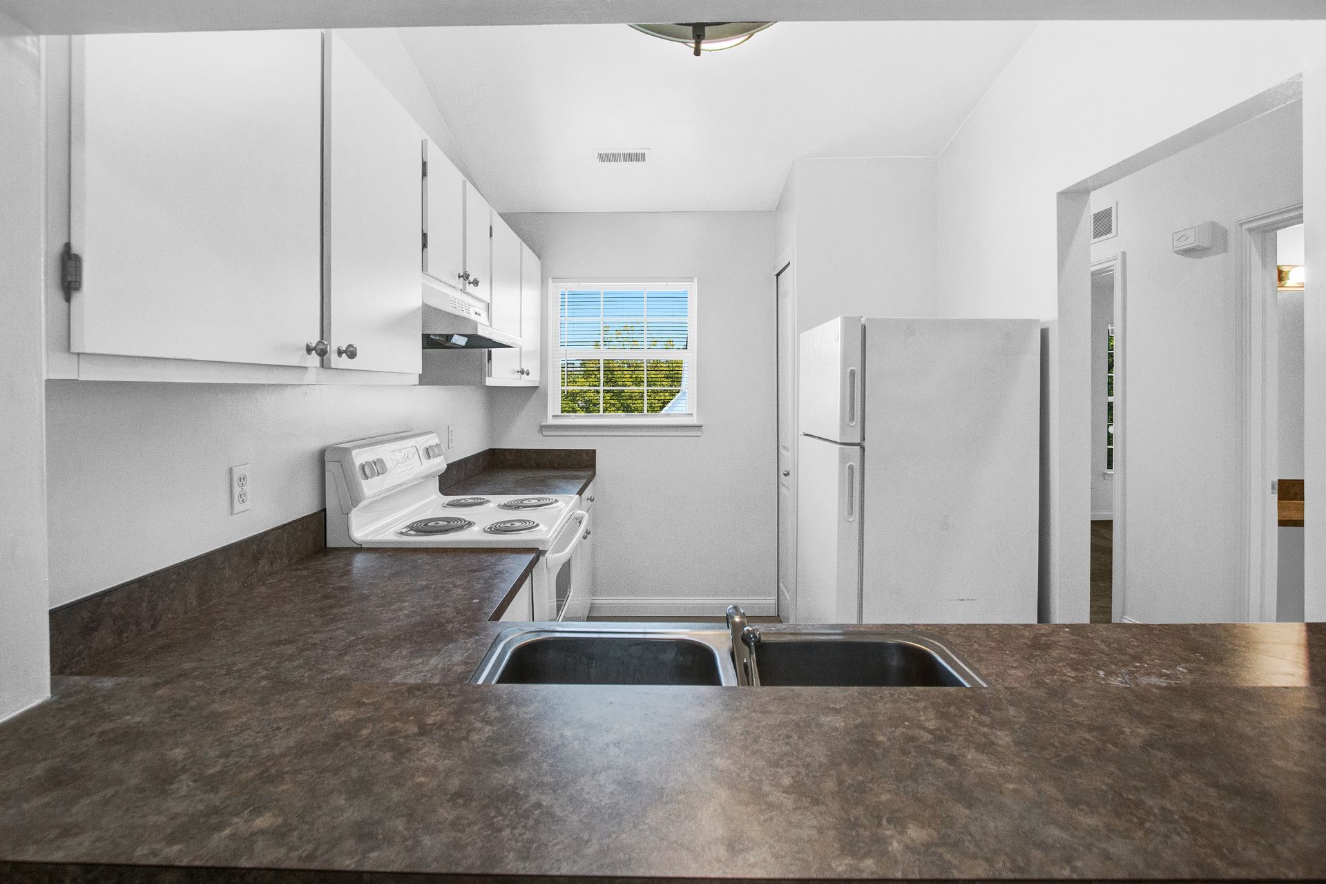A kitchen with a stove , refrigerator , sink and window.