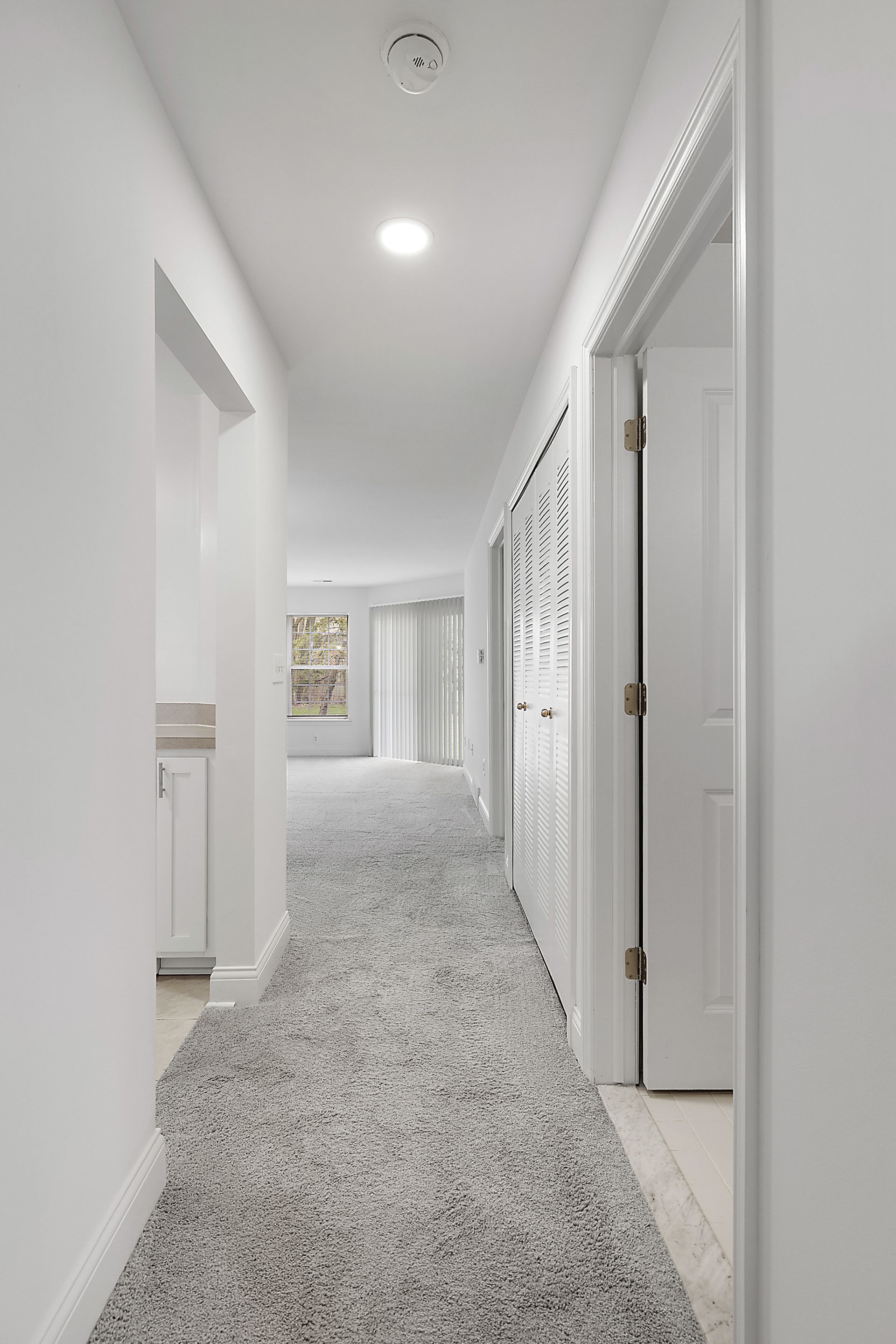 A long hallway with a carpeted floor and white walls in a house.