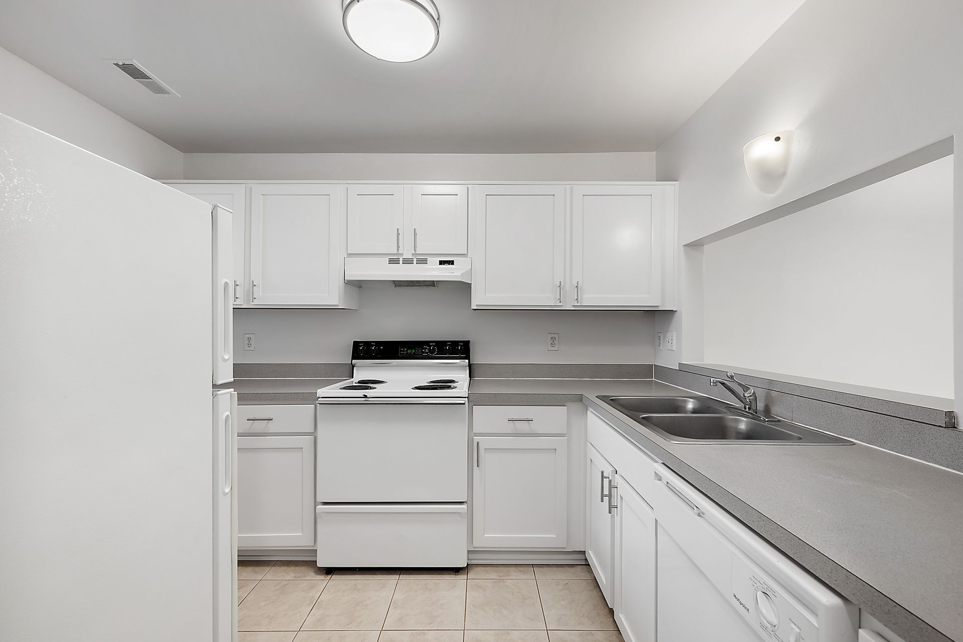 A kitchen with white cabinets a stove a refrigerator and a sink
