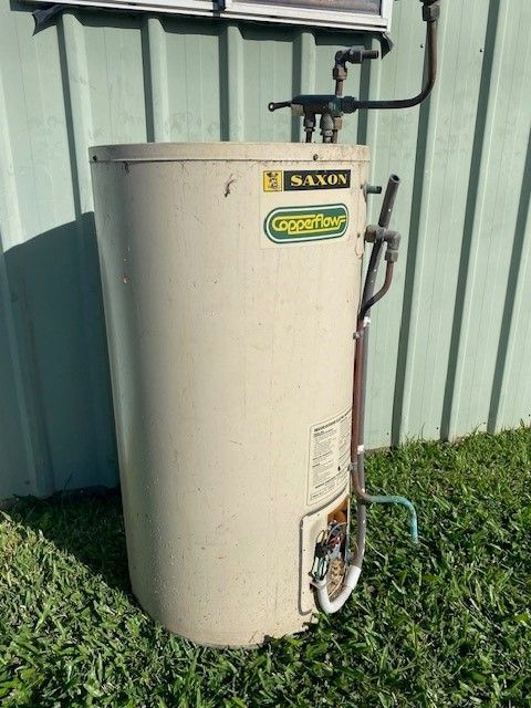 Beige Saxon Gas Hot Water Heater With Pipes And Valves Outdoors On Grass — David Talbot Plumbing in Cranbrook, QLD