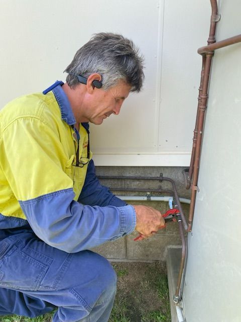 Smiling Man In Work Clothes Standing By White Van With Door Open Blue Background — David Talbot Plumbing in Cranbrook, QLD