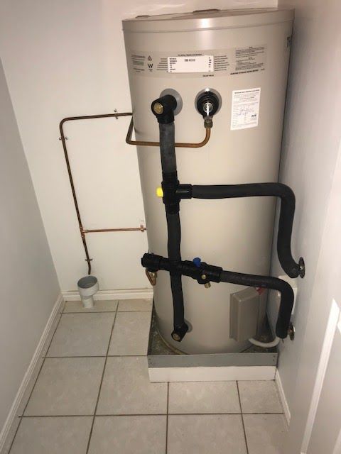 Hot Water Heater In Small White Room With Black And Copper Pipes — David Talbot Plumbing in Cranbrook, QLD