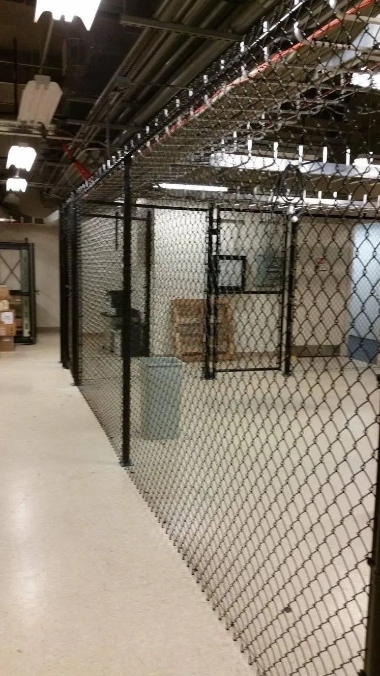 A chain link fence is surrounding a room in a building.