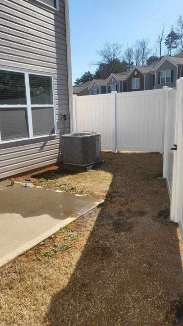 There is a white fence in the backyard of a house.