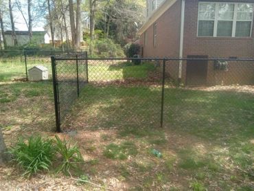 A chain link fence is in the backyard of a house
