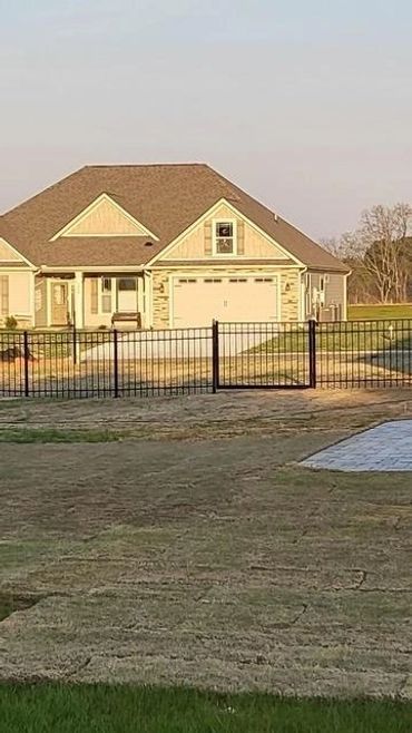 A house with a fence around it and a driveway in front of it.