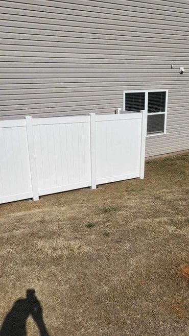 A white fence is in front of a house with a window.