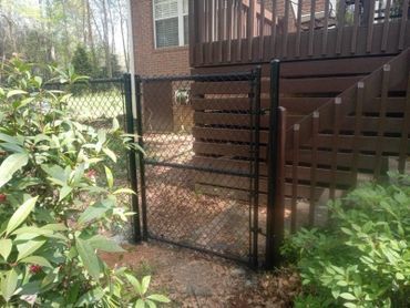 A chain link fence with a gate in front of a house.