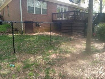 There is a chain link fence in the backyard of a house.