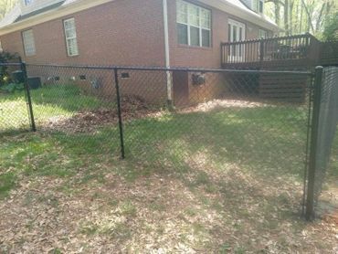 There is a chain link fence in the backyard of a house.