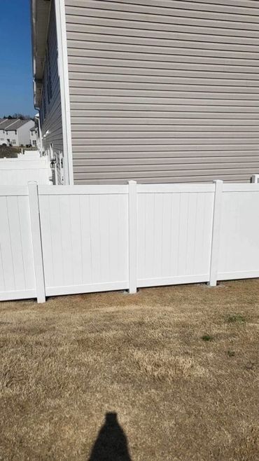There is a white fence in front of a house.
