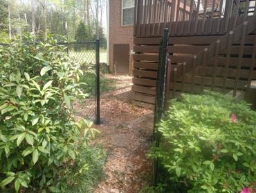 There is a chain link fence in the backyard of a house.
