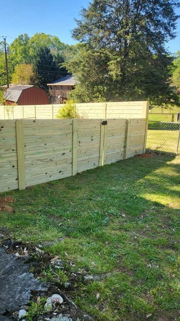 A wooden fence is sitting in the middle of a lush green yard.
