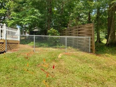 There is a chain link fence in the backyard of a house.
