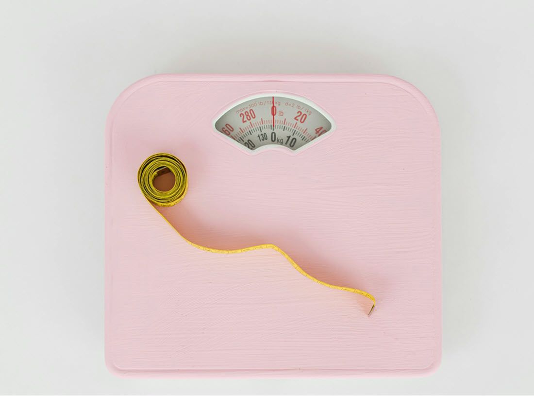 Pink scale with a yellow measuring tape draped over it.
