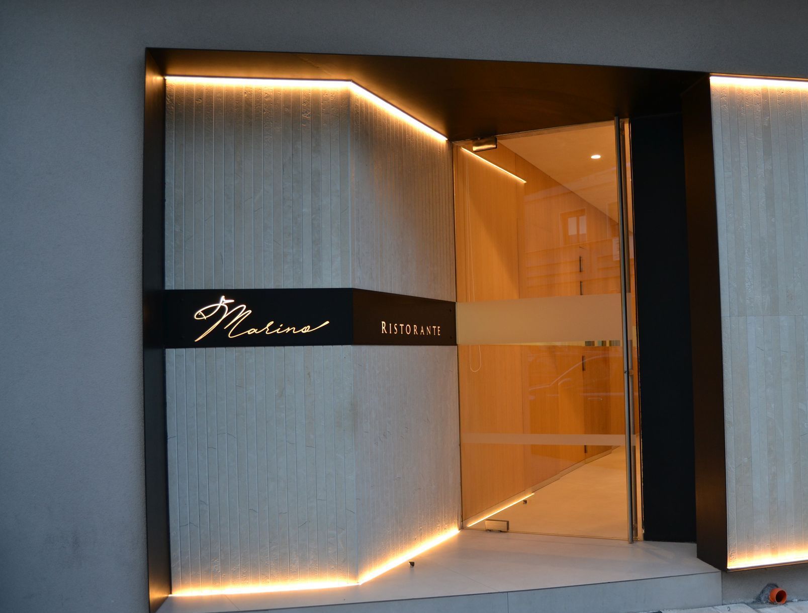 Un'auto è parcheggiata davanti a un ristorante con tavoli e sedie alla finestra.