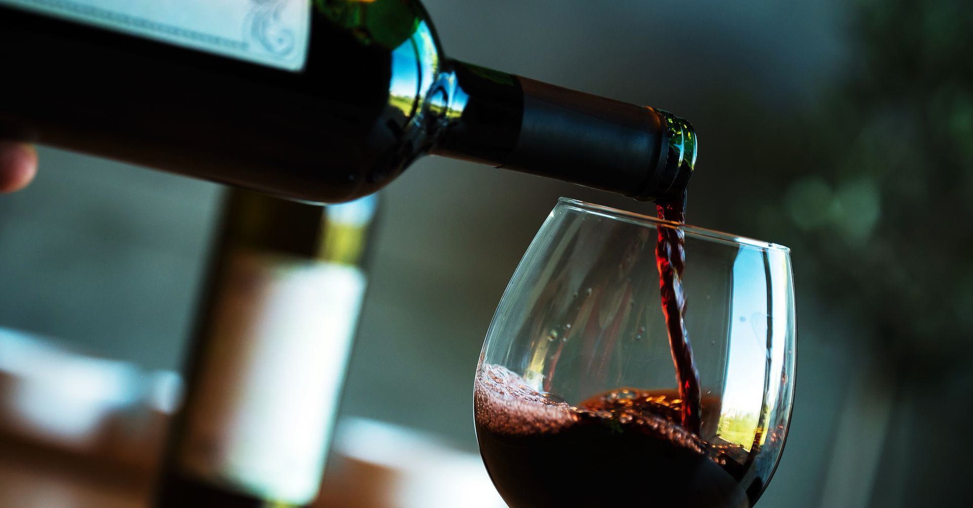 Una persona sta versando del vino rosso in un bicchiere.