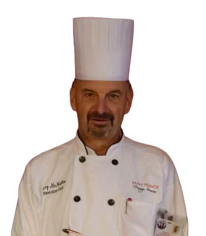 Chef in white chef's hat and coat, smiling. 