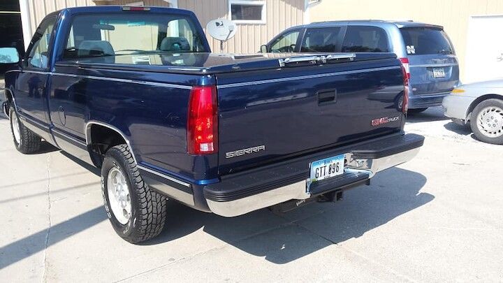 A blue pickup truck is parked in front of a building.