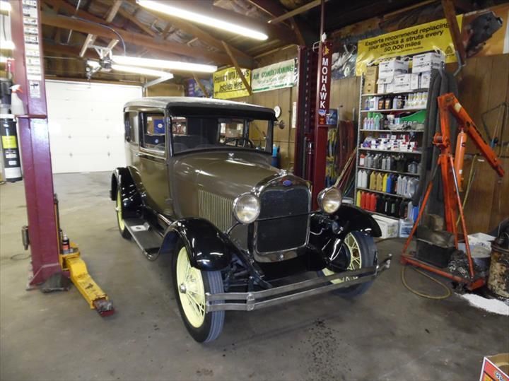 An old car is on a lift in a garage