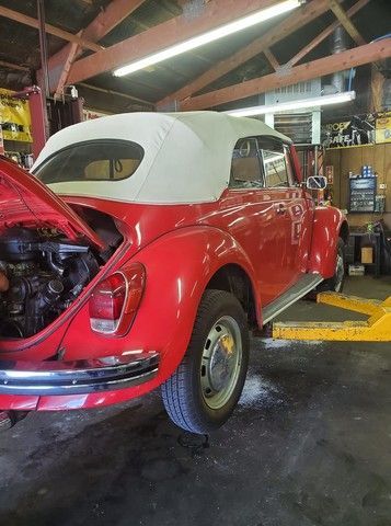 A red car with the hood open is parked in a garage.