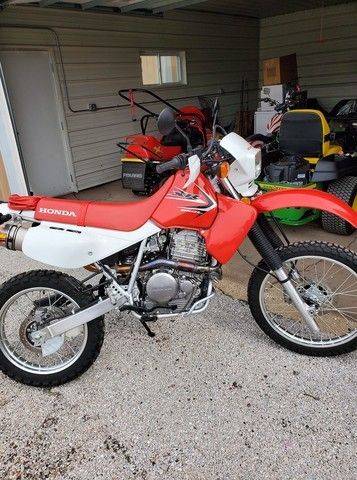 A red and white honda dirt bike is parked in a garage.