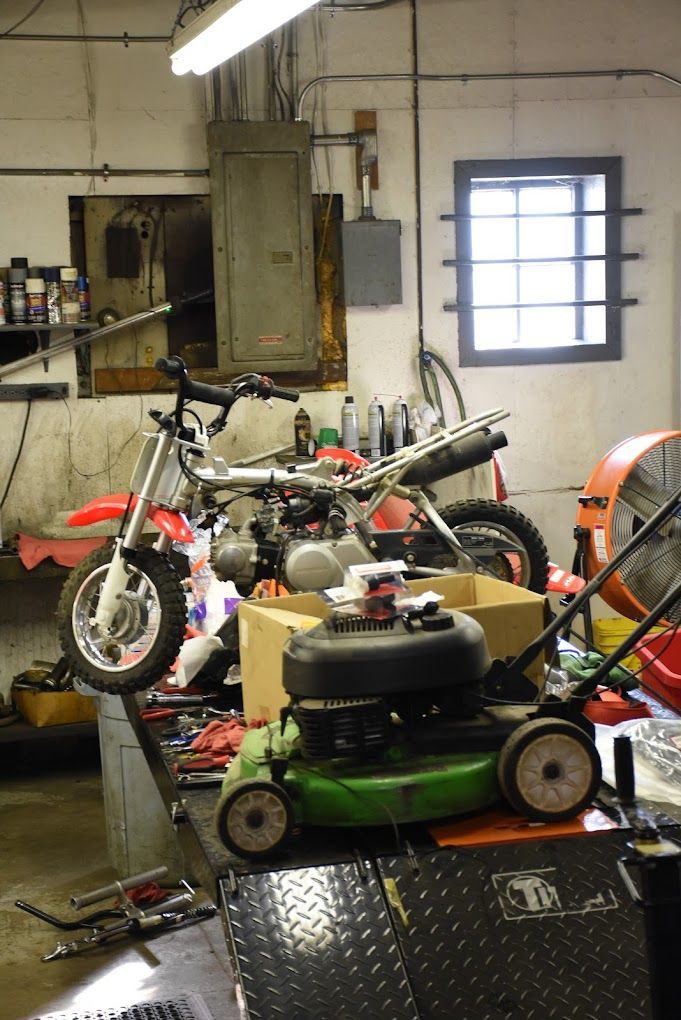 A green lawn mower sits on a table in a garage