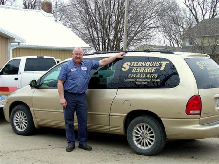 A man standing next to a van that says sternquist garage