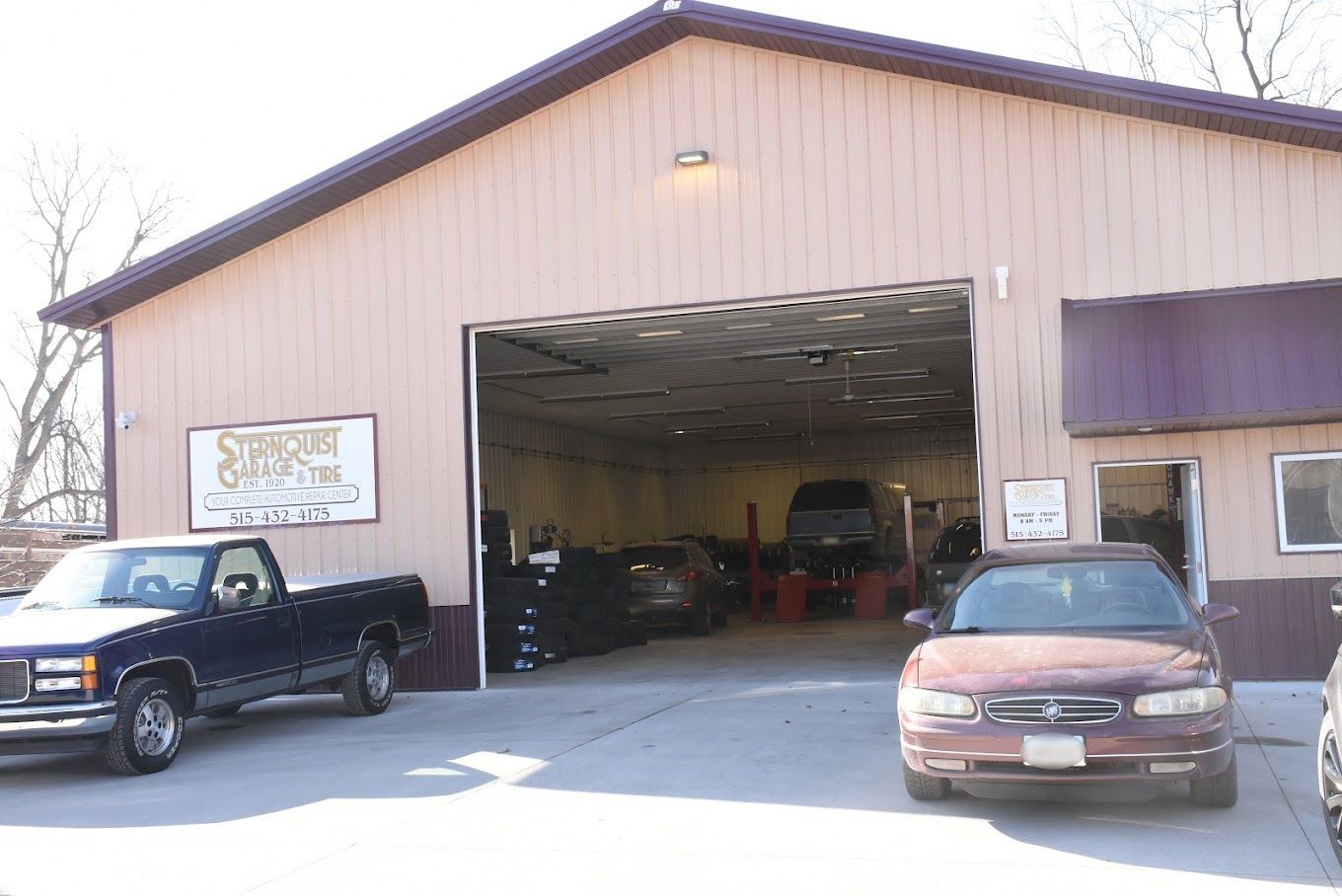 A truck and a car are parked in front of a garage.