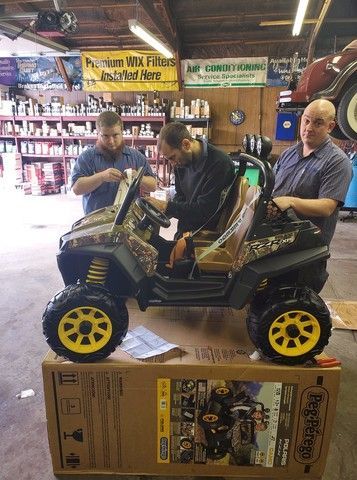 Two men are working on a toy atv in a garage.