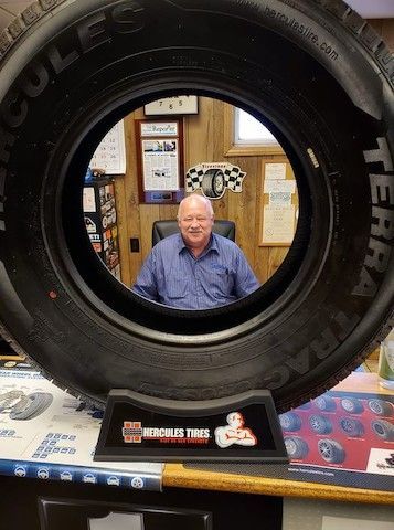 A man is sitting in a chair in front of a tire.