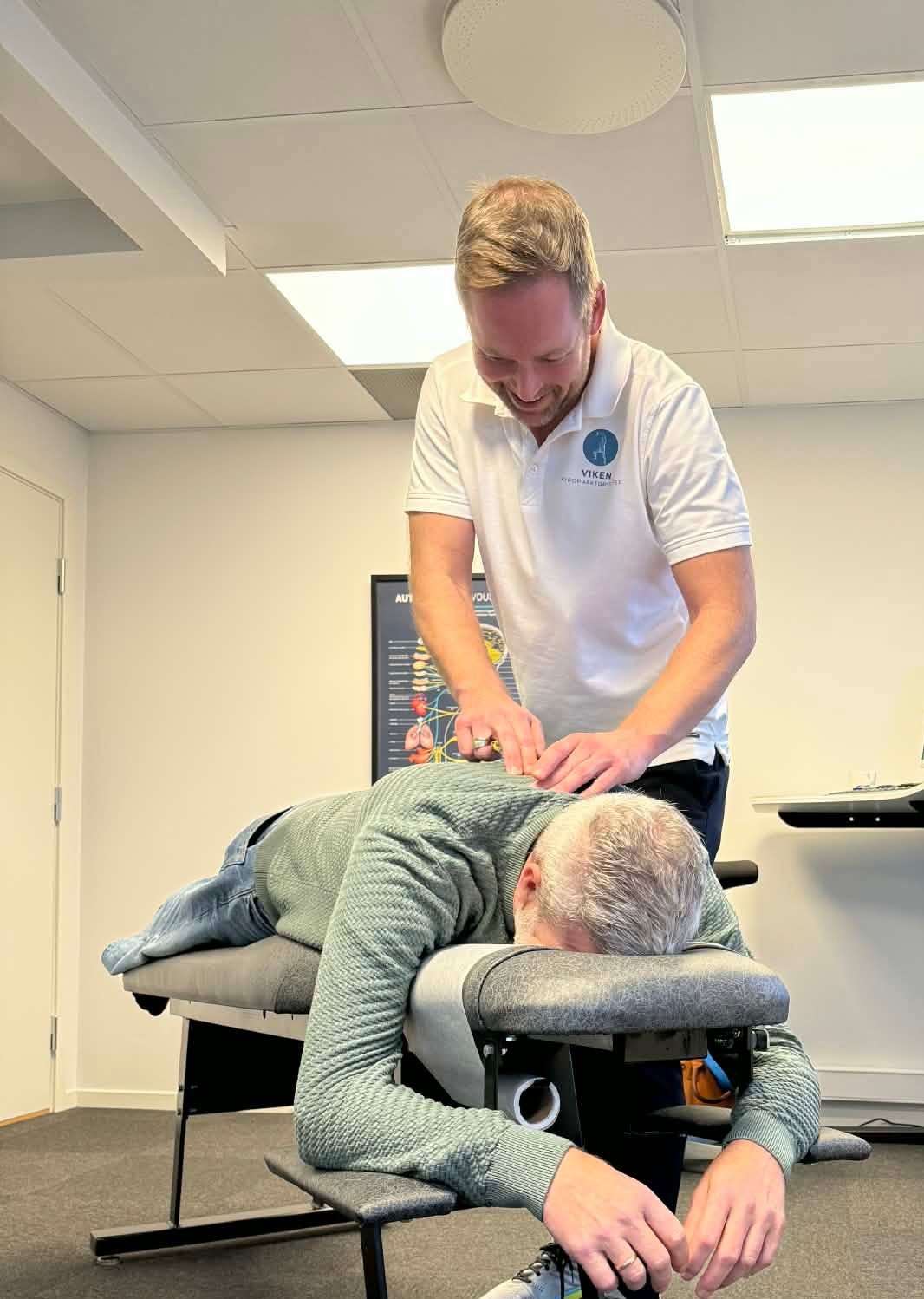 En persons rygg blir undersøkt av helsepersonell. Hendene presser forsiktig på personens rygg.