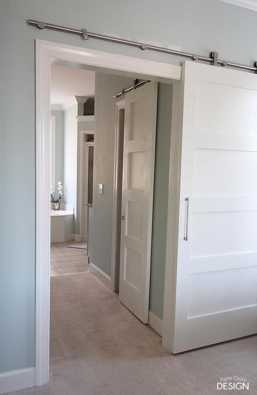 a bedroom with a sliding barn door leading to a bathroom .