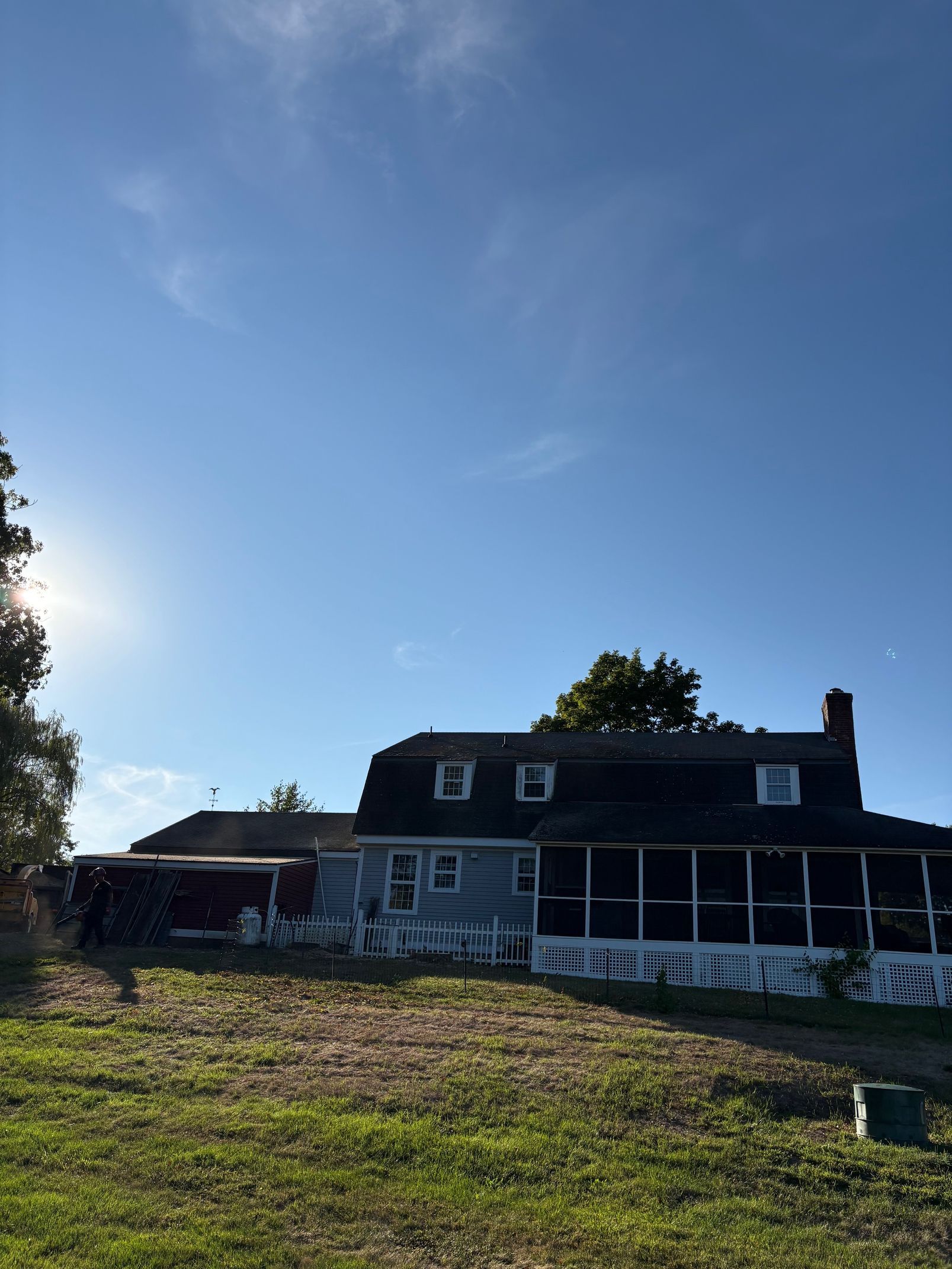 A blue house with a screened porch under a bright blue sky.
