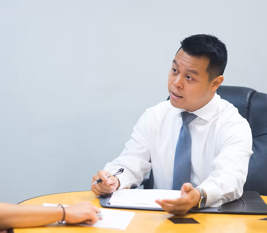 A man with a backpack is standing next to a lake in the woods.