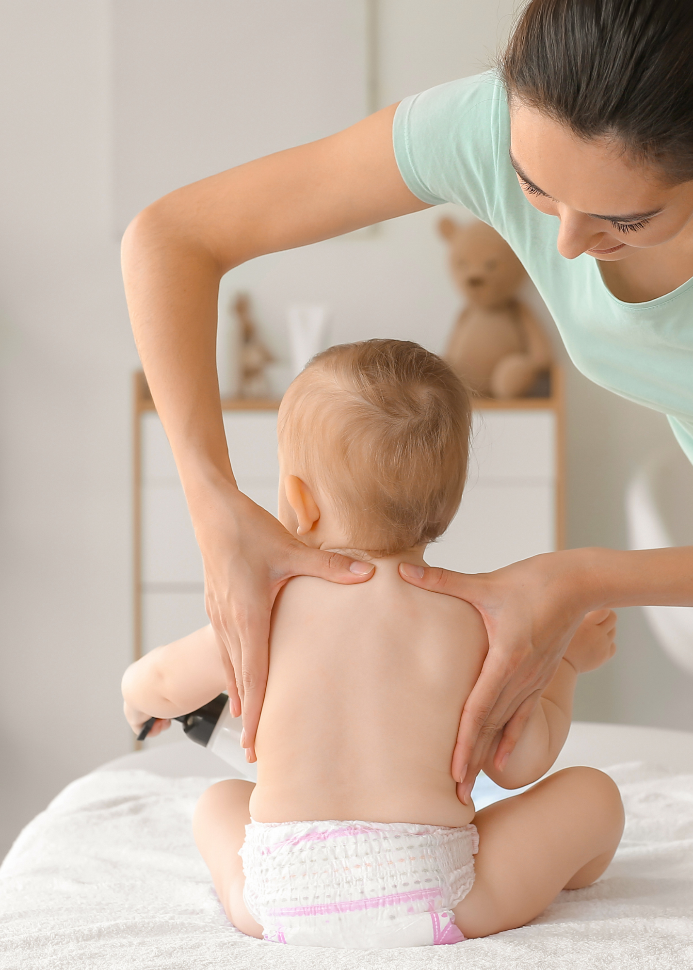 A woman is giving a baby a massage on a bed.