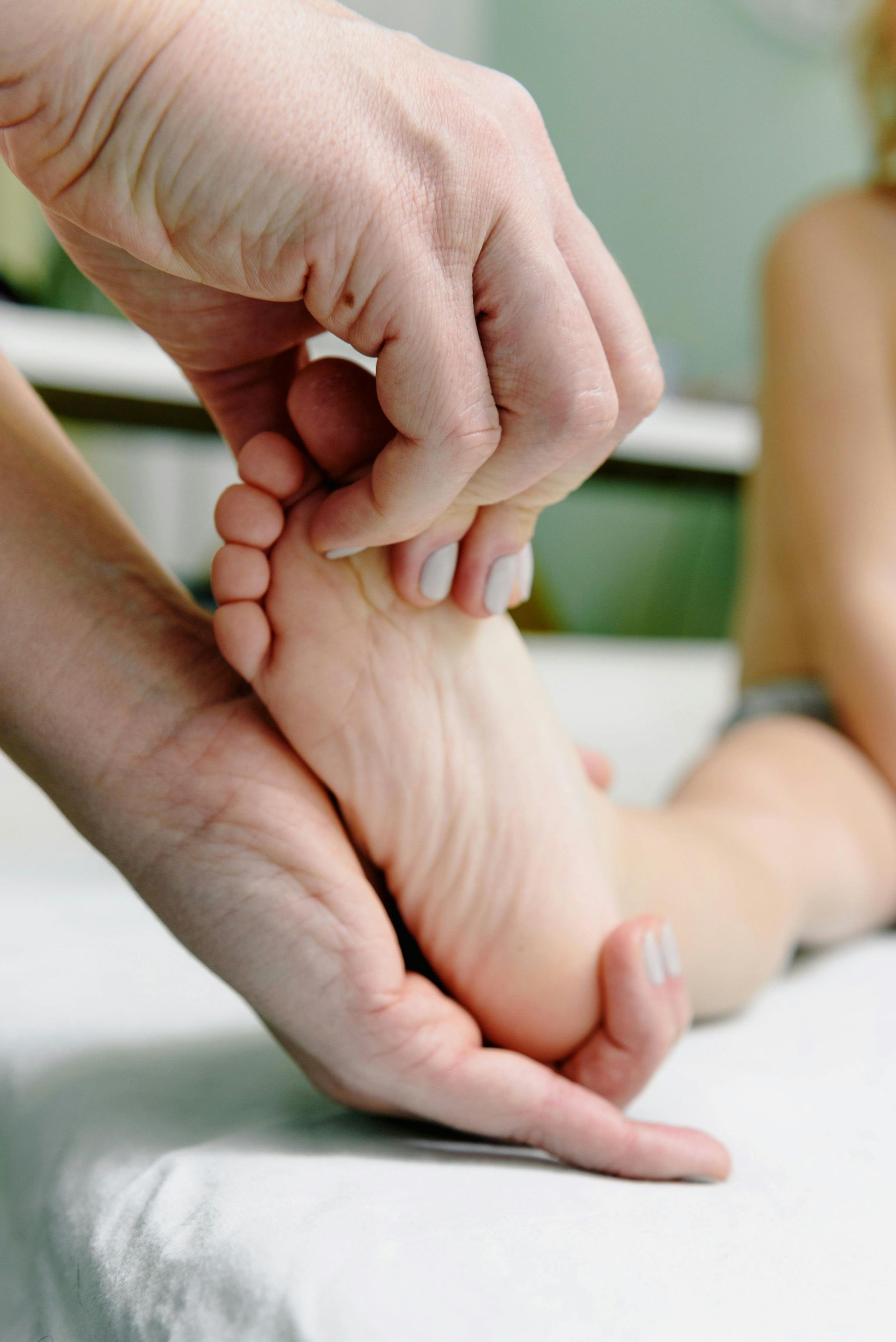 A person is massaging a child 's foot on a bed