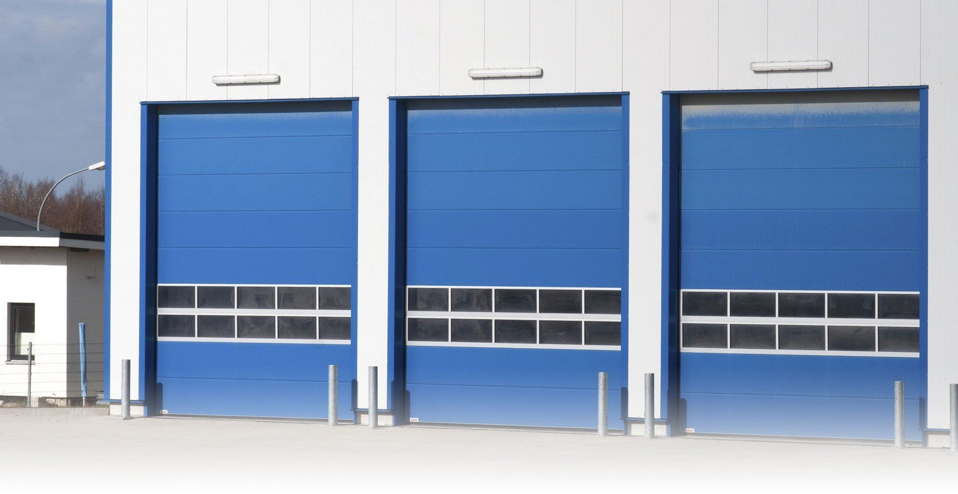 Tre porte da garage blu sono allineate sul lato di un edificio