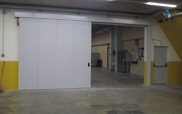Una grande porta scorrevole bianca è aperta in un magazzino
