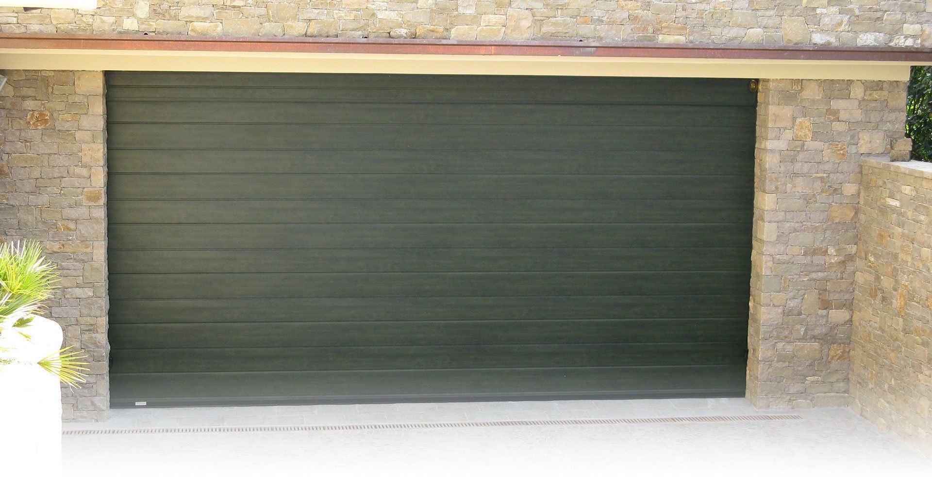 Una porta da garage nera con un muro di pietra dietro