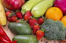 A vibrant assortment of fresh produce including strawberries, avocados, zucchini, an orange, a banana, and broccoli.