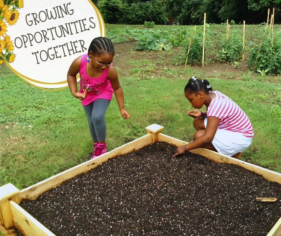 Two children gardening at a raised wooden planter box. Text in the corner reads, 