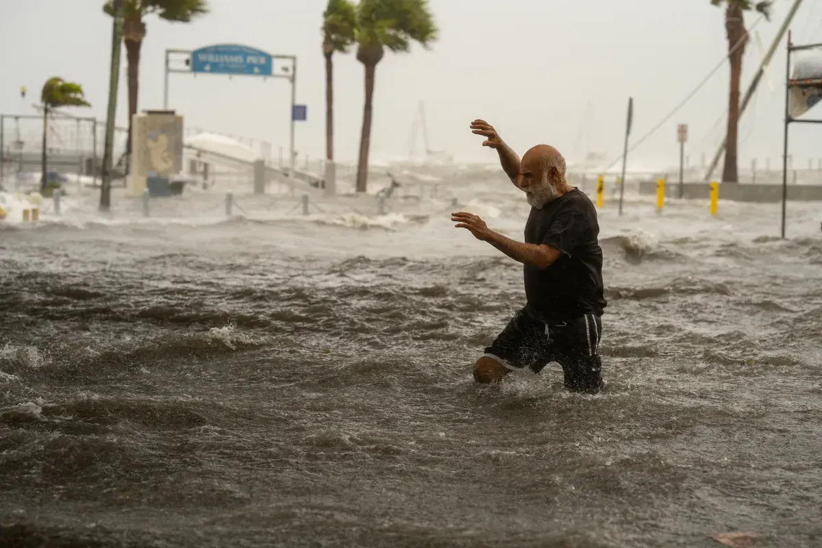 A man is walking through a flooded street during a hurricane.