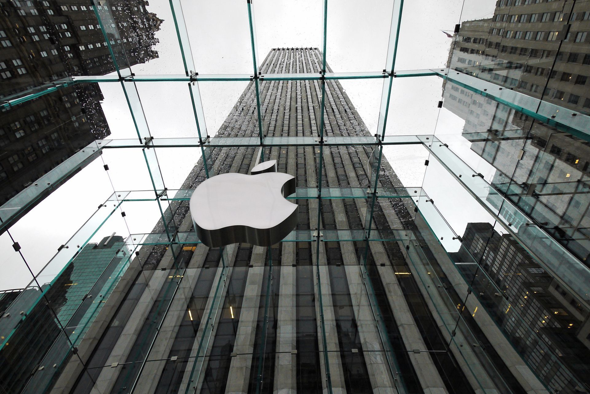 Looking up at the apple logo on top of a glass building