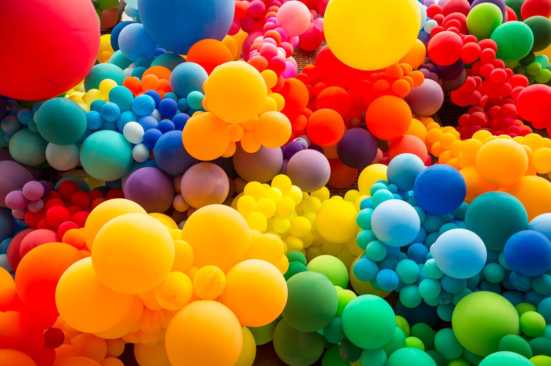Vibrant cluster of colorful balloons in a balloon rainbow of colors.